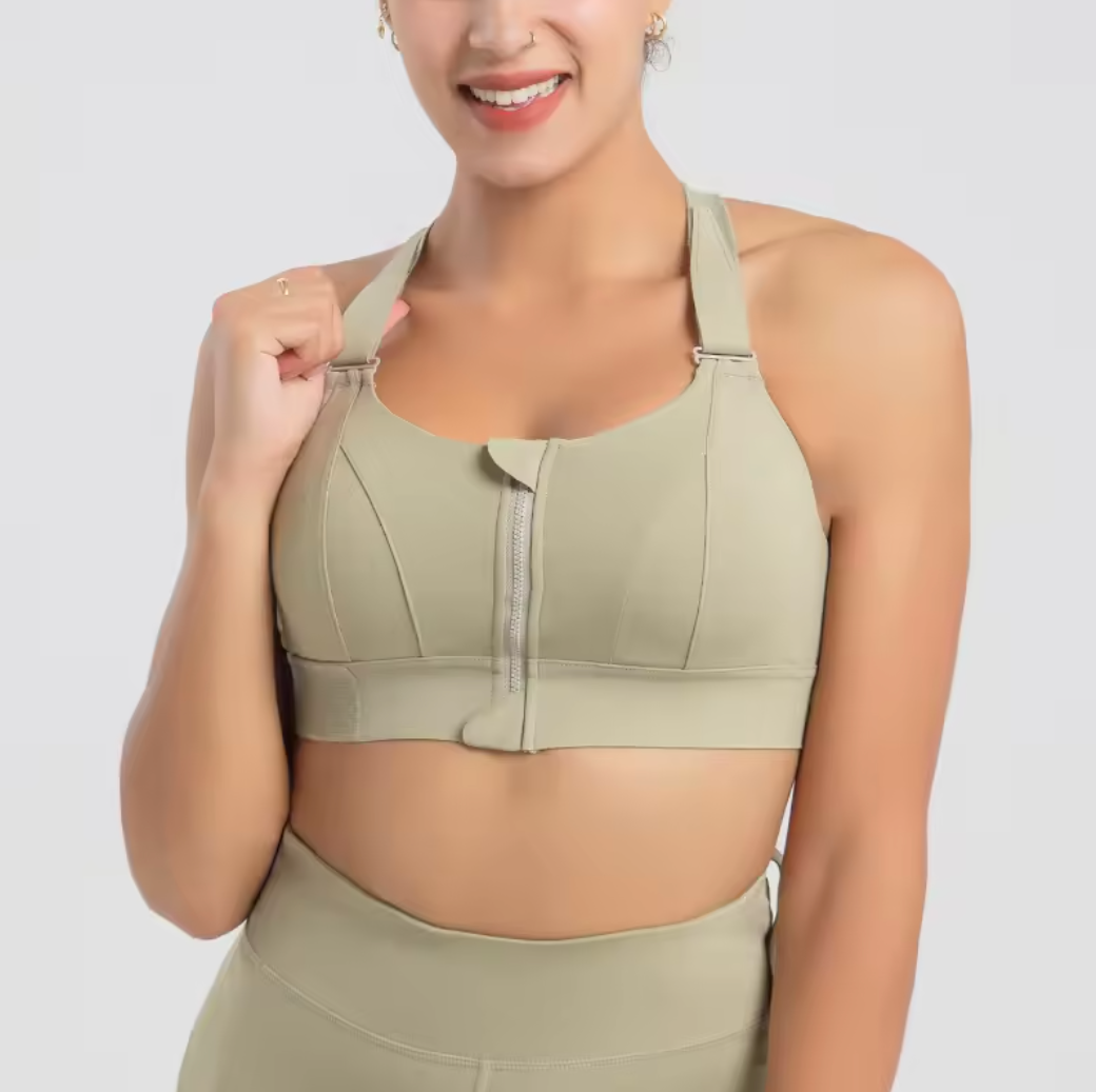 Femme souriante portant une brassière de sport beige avec fermeture éclair, idéale pour fitness et yoga. Mode active, confort et style.